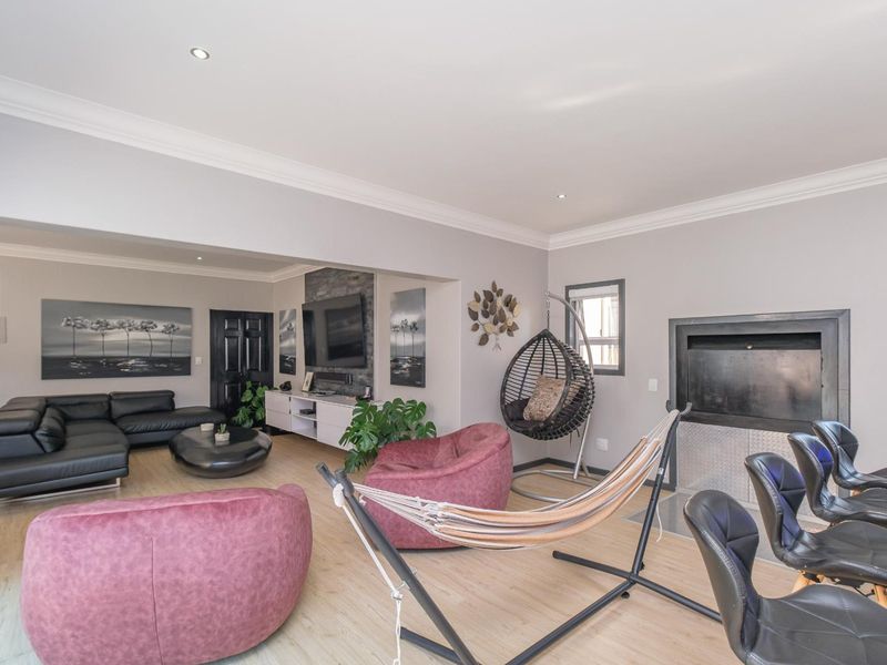 Spacious living area featuring a stone-clad fireplace, recessed downlighting, and light-toned laminate flooring, creating a modern and comfortable atmosphere.