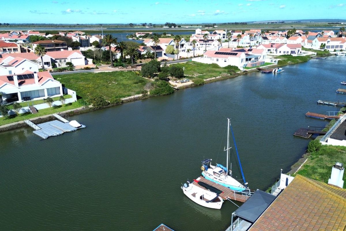 Aerial view of a residential canal-front property featuring a private jetty and direct water access within a coastal estate.