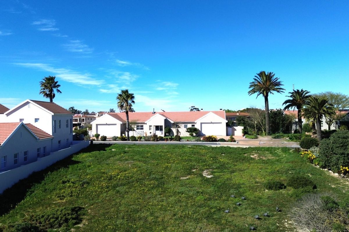 An elevated aerial view of a vacant residential plot situated within a developed neighborhood, offering a clear perspective of the land and surrounding properties.
