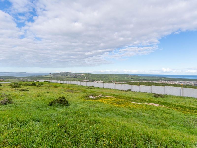 Expansive view of the vacant residential land featuring a perimeter boundary wall and surrounding coastal landscape.