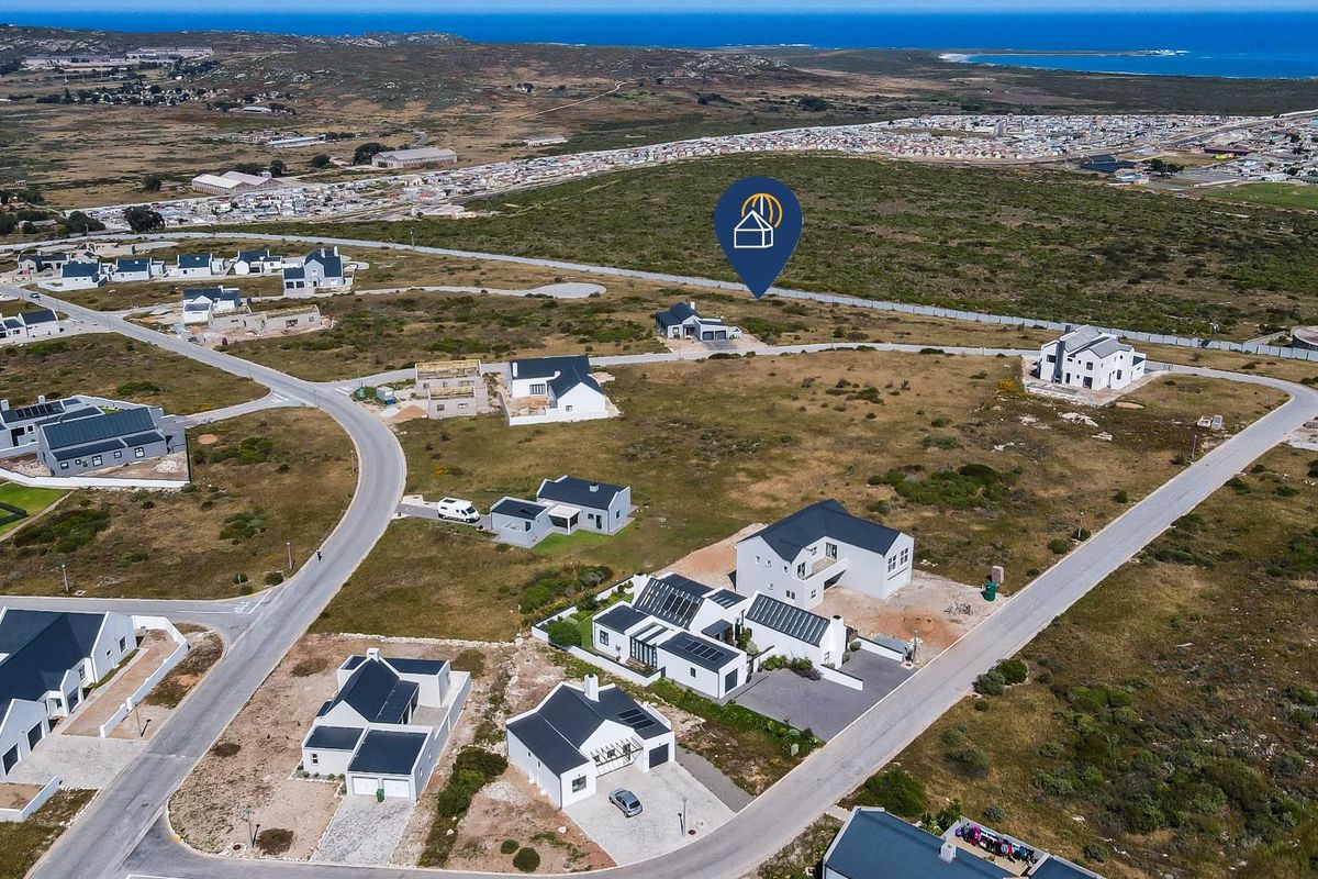 Aerial view of a residential development area featuring vacant plots and established modern homes with coastal surroundings.
