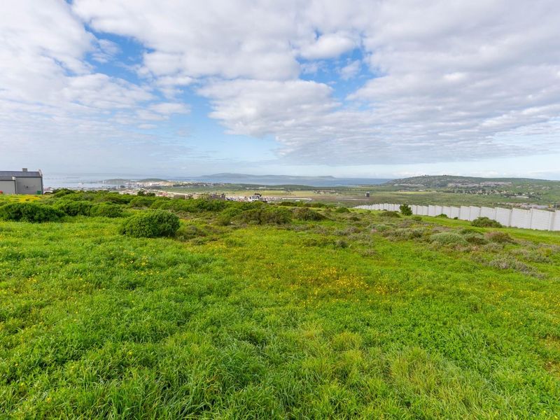 Expansive view of the surrounding landscape and coastline from the vacant residential plot, featuring a perimeter boundary wall.
