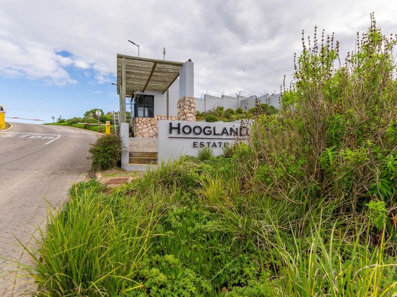 The entrance to Hoogland Estate featuring a security gatehouse, paved access road, and established landscaping.