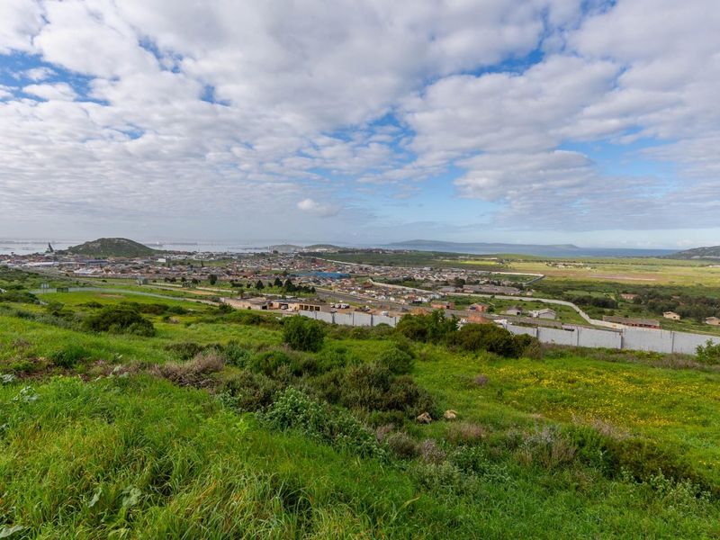 Expansive elevated view overlooking the surrounding residential landscape and distant coastal terrain from the vacant residential plot.