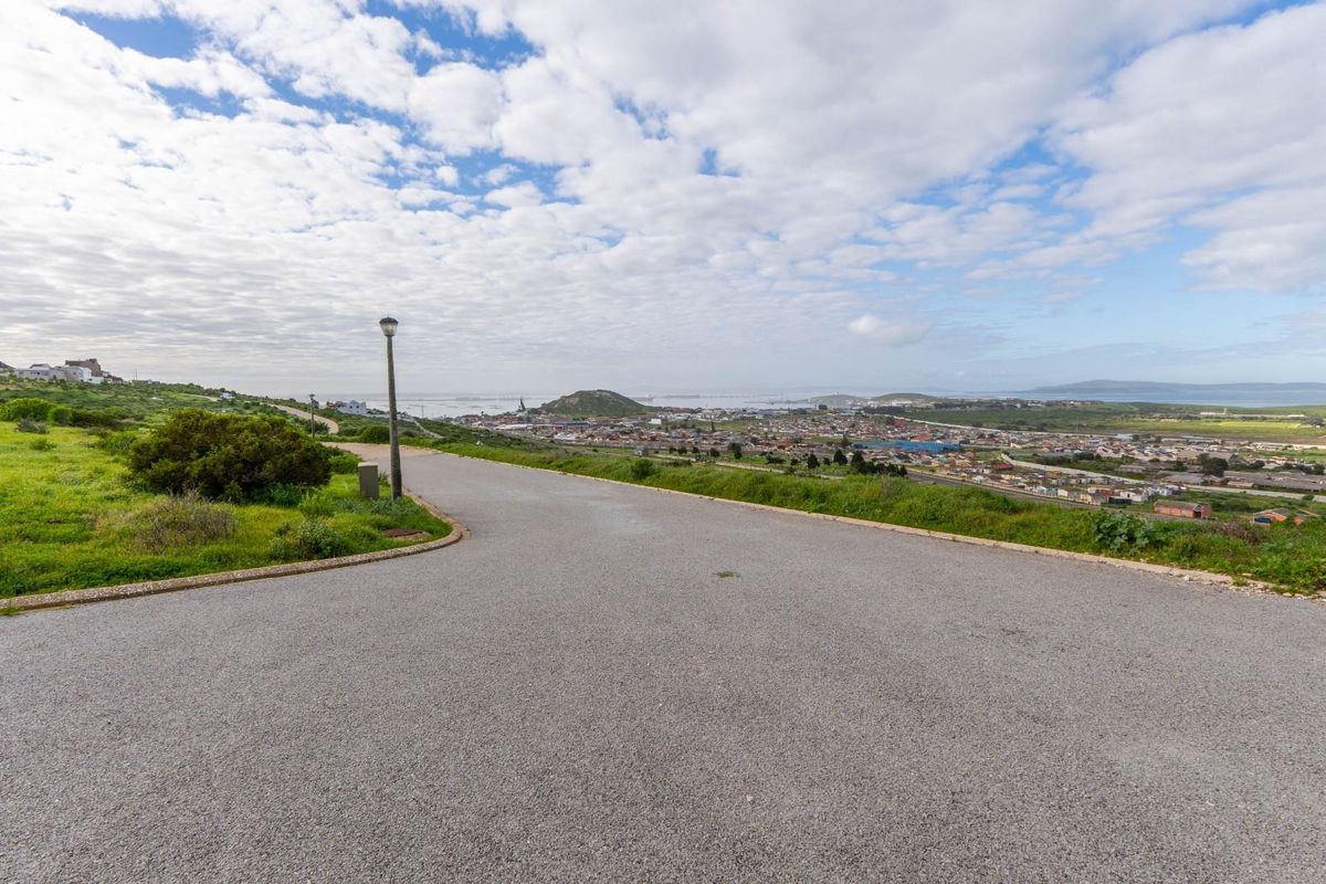 A scenic view overlooking the surrounding residential area and coastline from an elevated position on a paved road.
