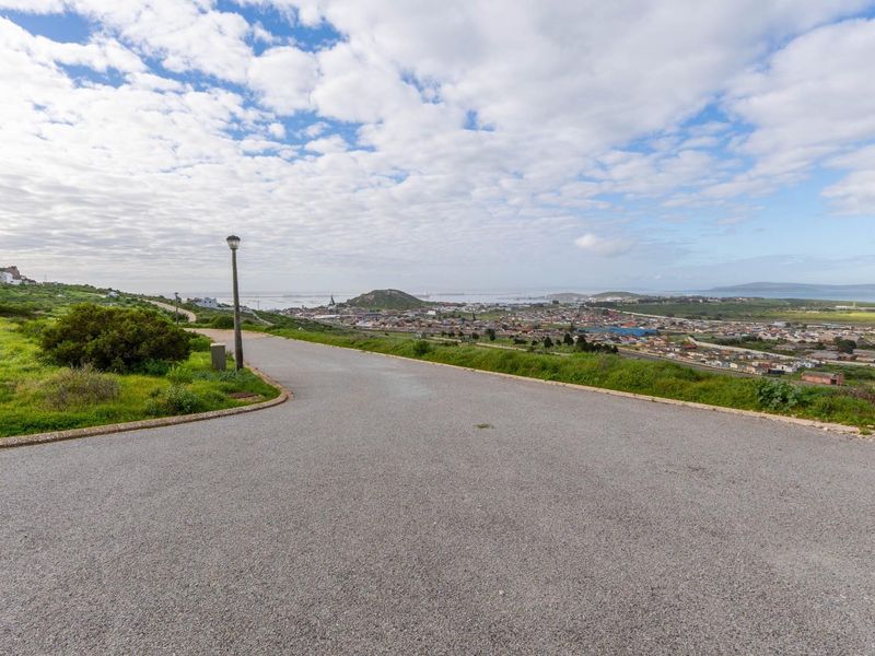 A scenic view overlooking the surrounding residential area and coastline from an elevated position on a paved road.