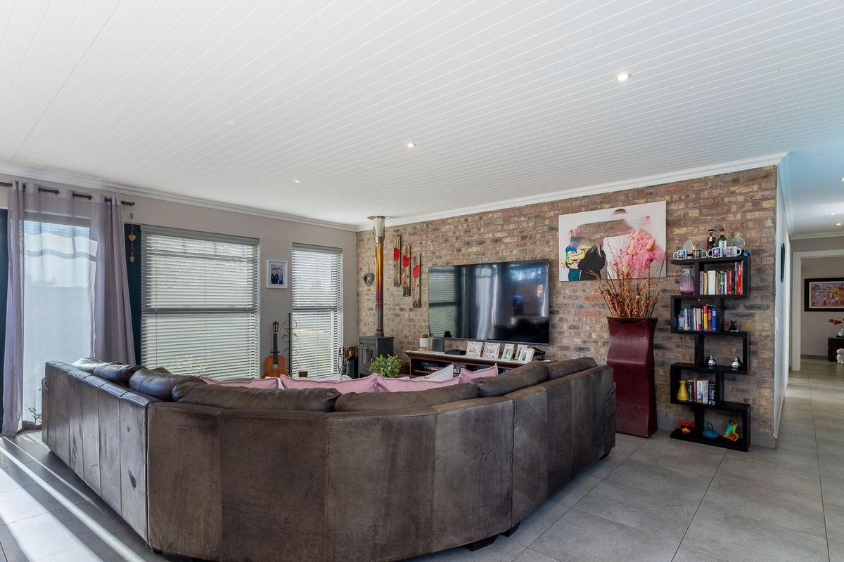 Spacious living room featuring an exposed brick feature wall, a wood-burning fireplace, tiled flooring, and direct access to the outdoor area via sliding doors.