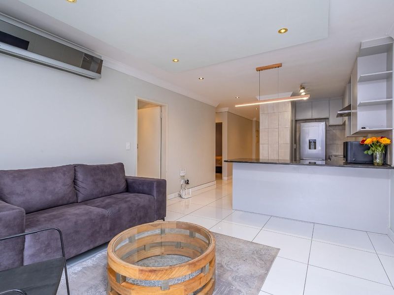 Modern open-plan living area featuring tiled floors, recessed lighting, a split-system air conditioner, and a functional kitchen with a breakfast island.