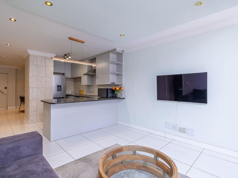 Modern open-plan living area featuring a sleek kitchen with granite countertops, breakfast bar, and tiled flooring throughout.