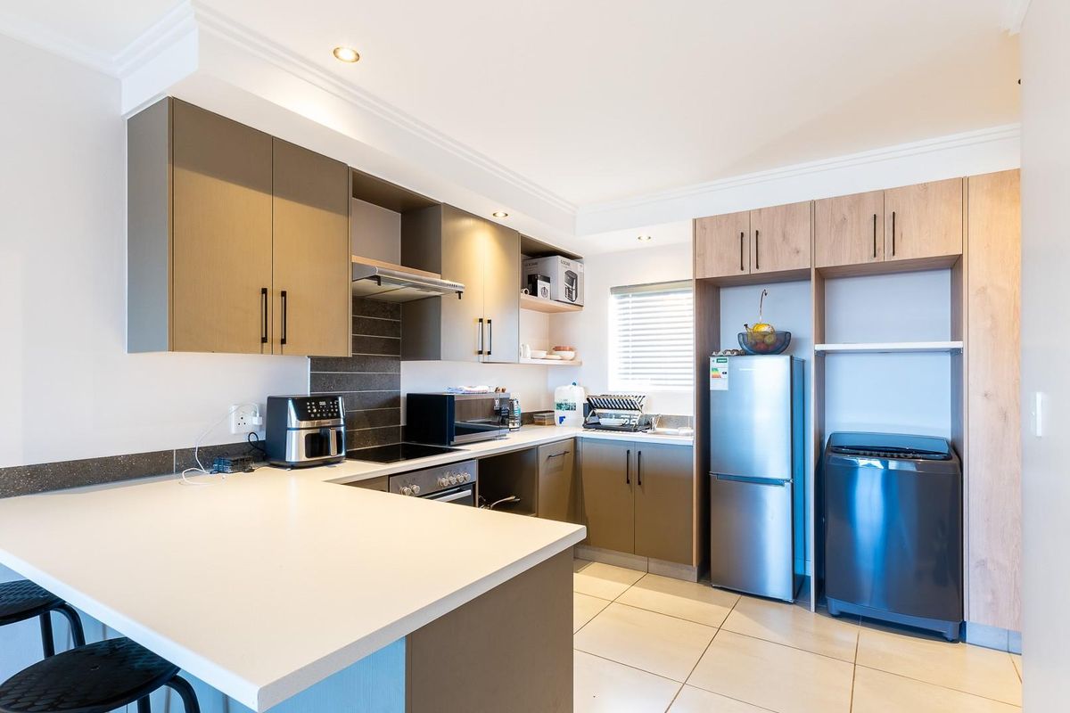 Modern kitchen featuring sleek built-in cabinetry, stone countertops, integrated appliances, tiled backsplash, and recessed lighting, offering a functional and contemporary cooking space.