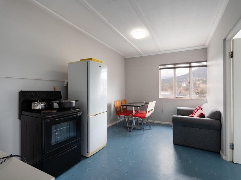 Open-plan living and kitchen area featuring vinyl flooring, a freestanding stove, and natural light from a window with mountain views.