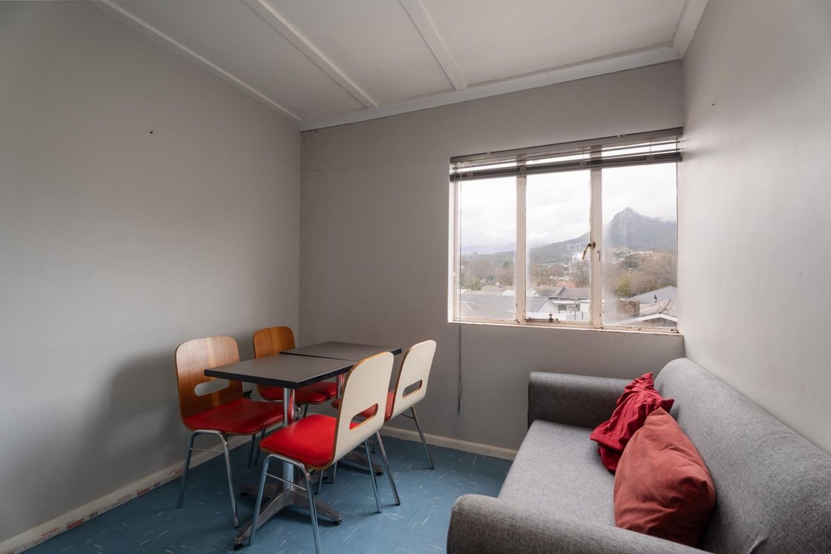 A compact living area featuring vinyl flooring, a window with venetian blinds, and views of the surrounding landscape.