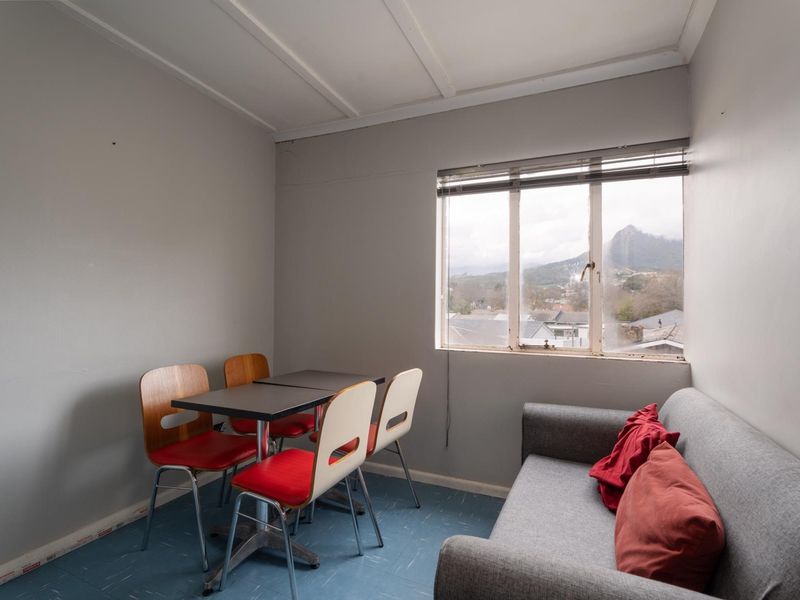 A compact living area featuring vinyl flooring, a window with venetian blinds, and views of the surrounding landscape.