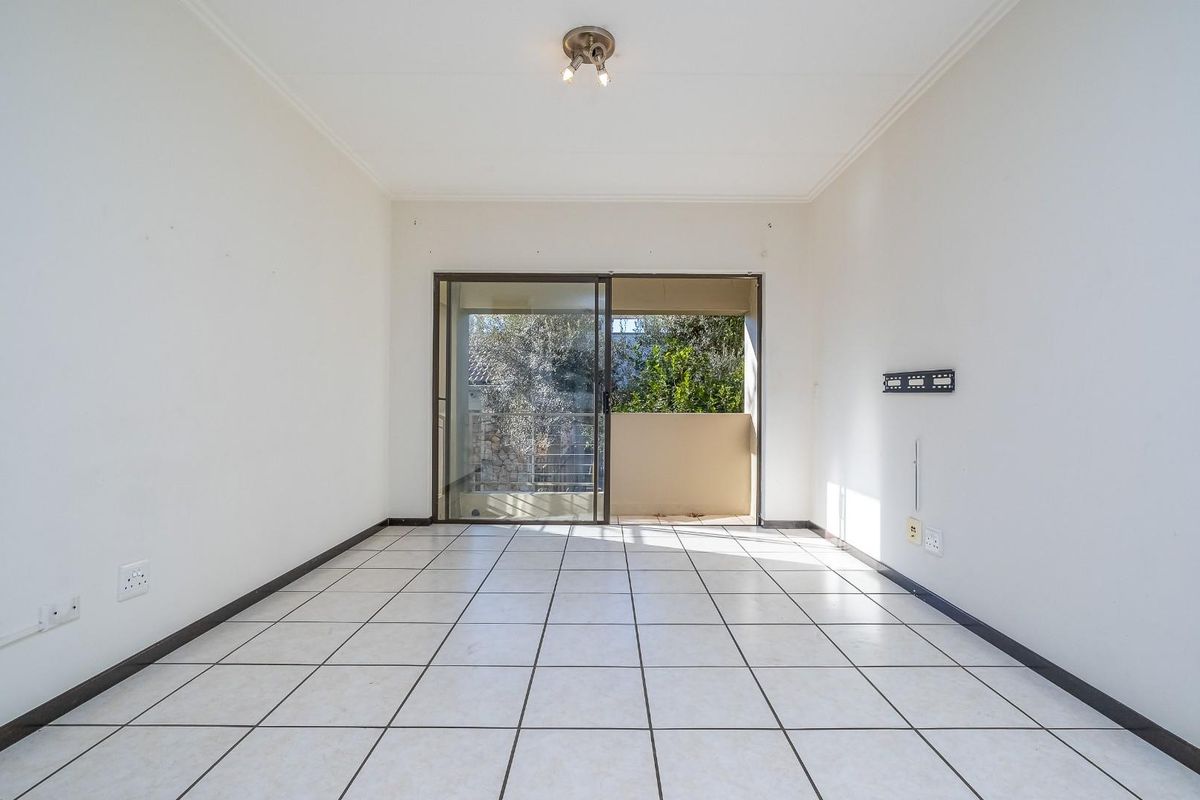 A bright, empty living room featuring tiled flooring and a sliding glass door that opens to an outdoor balcony area.