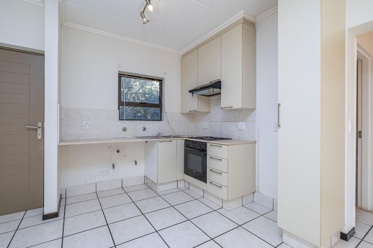A compact kitchen featuring tiled flooring, built-in cabinetry, an integrated oven and hob, and a tiled splashback, currently awaiting minor repairs and updates.