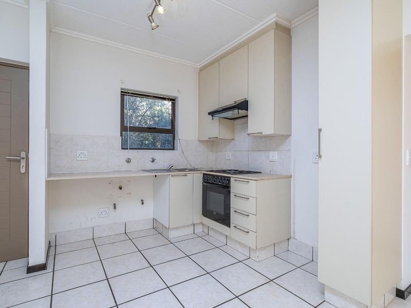 A compact kitchen featuring tiled flooring, built-in cabinetry, an integrated oven and hob, and a tiled splashback, currently awaiting minor repairs and updates.
