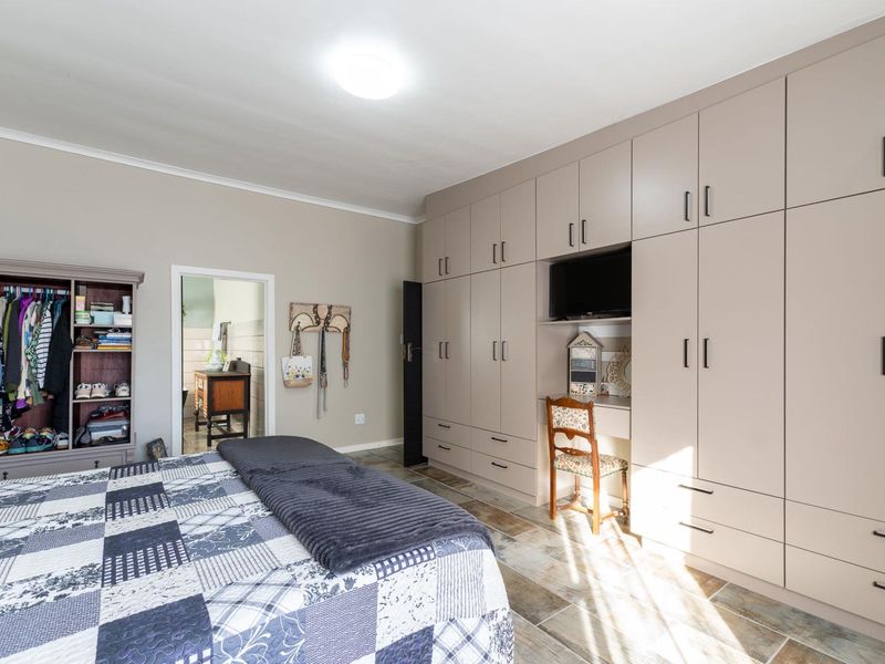 Spacious bedroom featuring extensive floor-to-ceiling built-in cupboards with an integrated desk area and durable tiled flooring.
