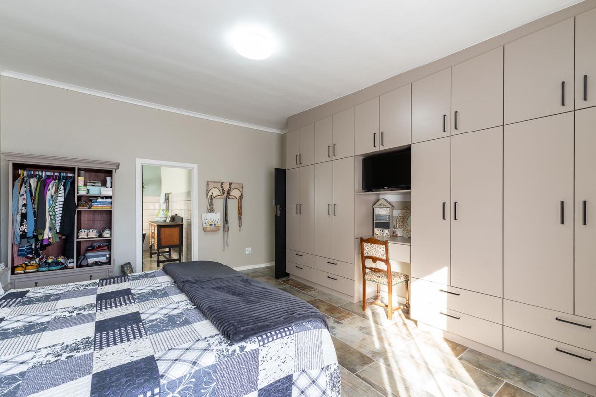 Spacious bedroom featuring extensive floor-to-ceiling built-in cupboards with an integrated desk area and durable tiled flooring.