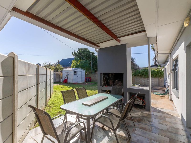Covered outdoor patio featuring a built-in braai, tiled flooring, and direct access to the rear garden area.