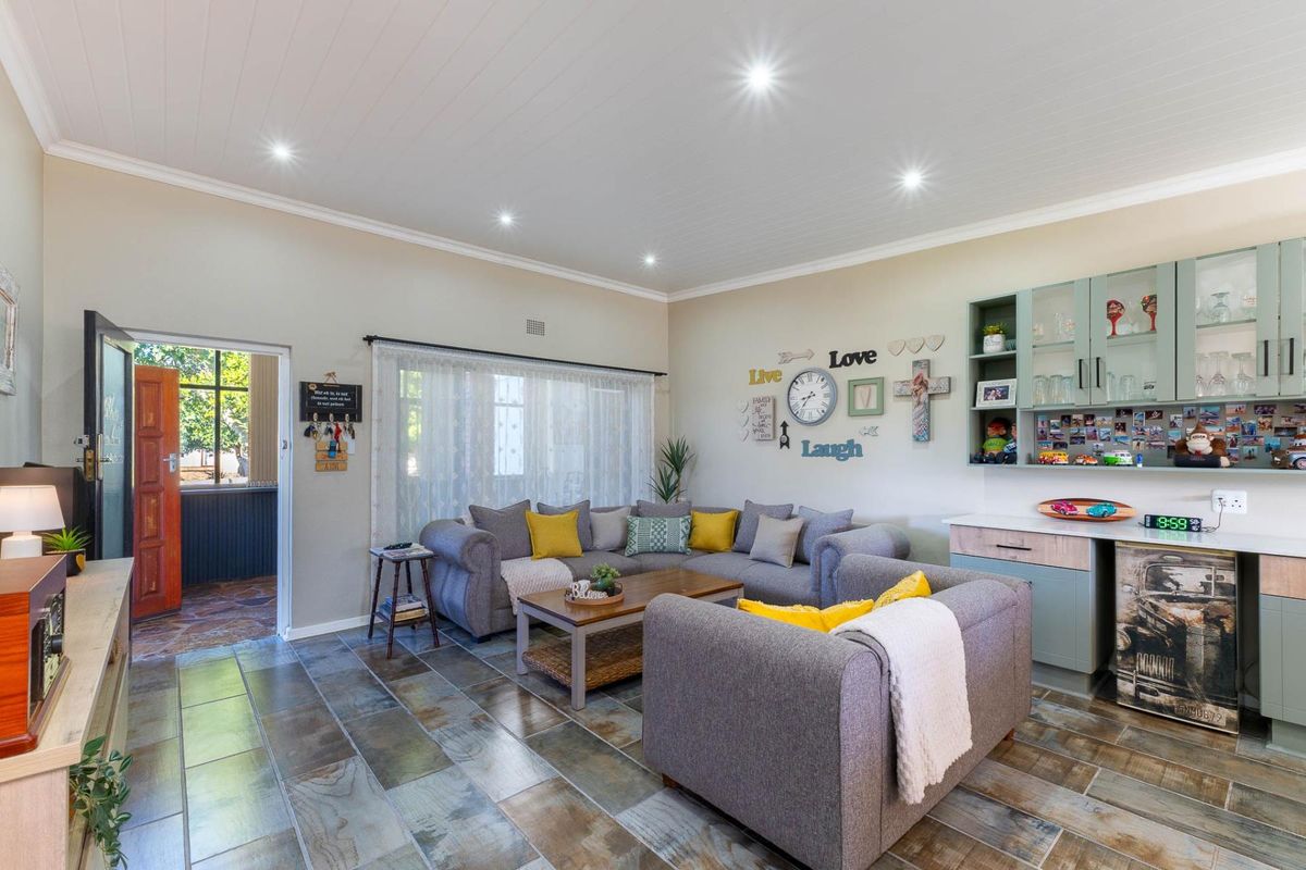 A comfortable living room featuring tiled flooring, a tongue and groove ceiling with recessed lighting, and built-in cabinetry for storage.