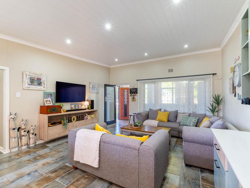 Open-plan living area featuring timber-look tiled flooring, recessed downlighting, and a tongue and groove ceiling, providing a bright and functional space.