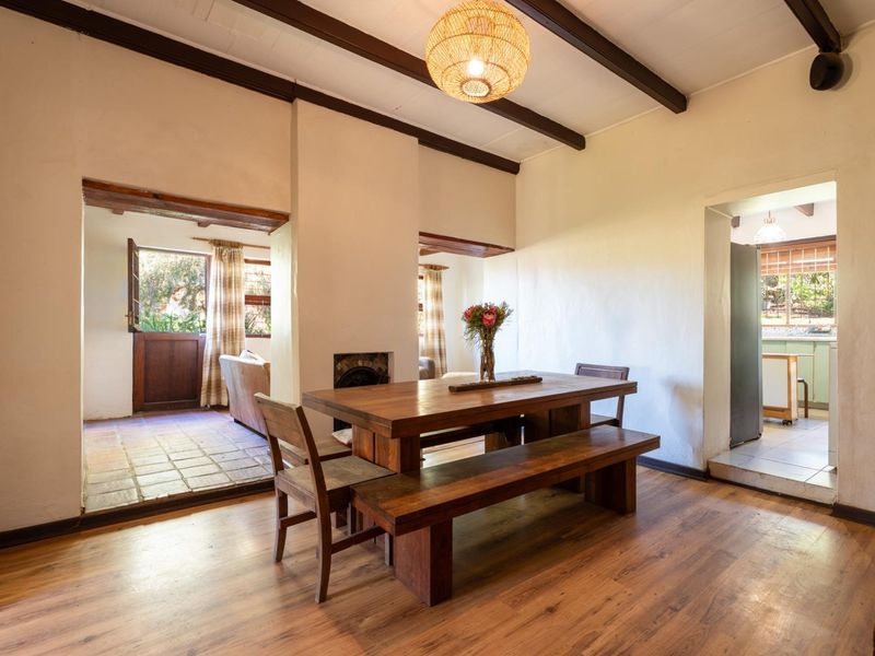 Dining room featuring exposed timber ceiling beams, laminate flooring, and a built-in fireplace, with direct access to adjacent living and kitchen areas.