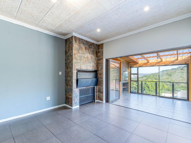 Spacious living area featuring a built-in fireplace, tiled flooring, and large stacking doors opening onto a covered patio with scenic views.