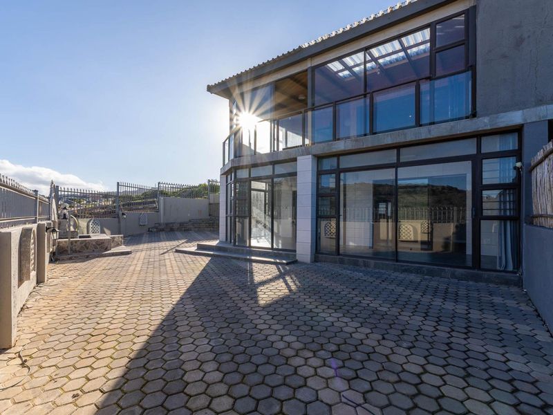 Rear exterior view of the townhouse featuring a paved patio area, glass sliding doors, and an upper-level balcony with metal railings.