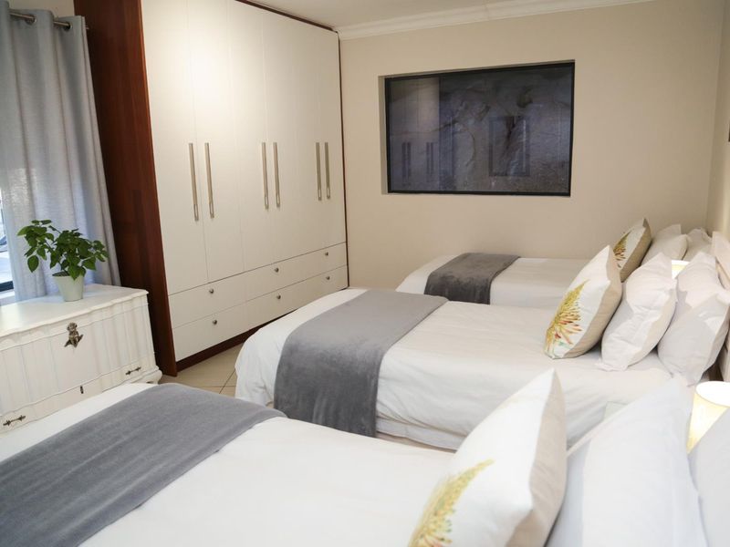 A well-maintained bedroom featuring extensive built-in cupboards and a recessed window, providing ample storage and a clean, functional layout.