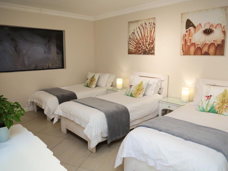 A well-maintained bedroom featuring neutral tiled flooring and coved ceiling details, currently configured with three single beds.