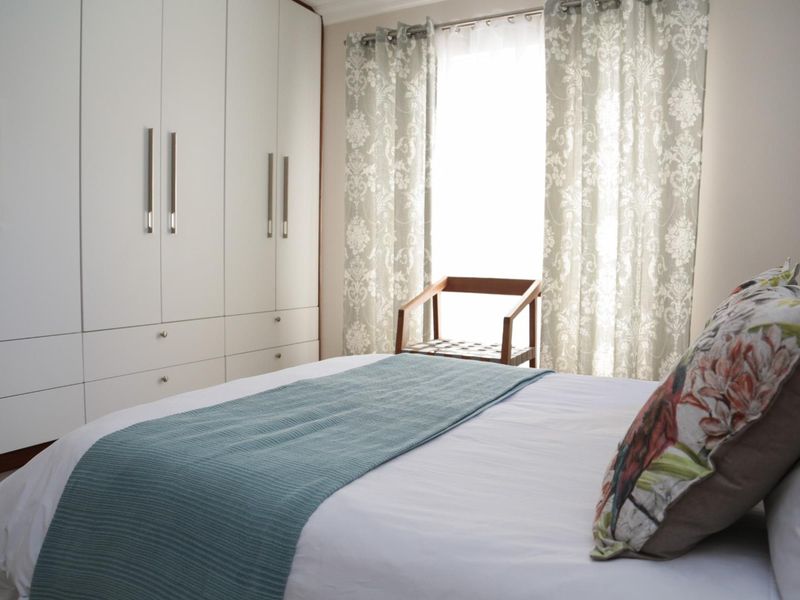 A well-maintained bedroom featuring floor-to-ceiling built-in cupboards and natural light from the window.