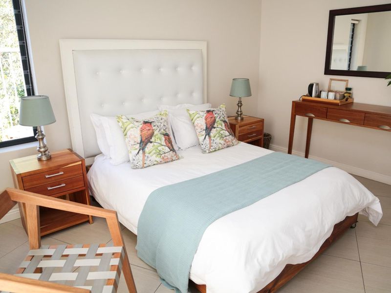 A well-maintained bedroom featuring neutral wall tones, tiled flooring, and a large window providing natural light.