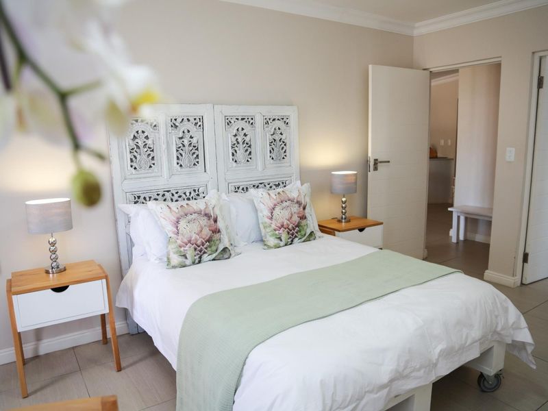A well-maintained bedroom featuring neutral wall tones, tiled flooring, and decorative coving, with an adjoining doorway leading to a secondary space.