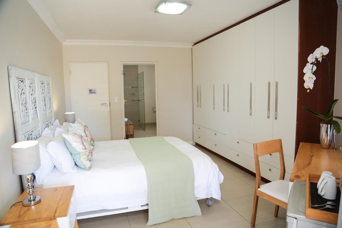 Spacious bedroom featuring extensive built-in cupboards, neutral tiled flooring, and direct access to an en-suite bathroom.