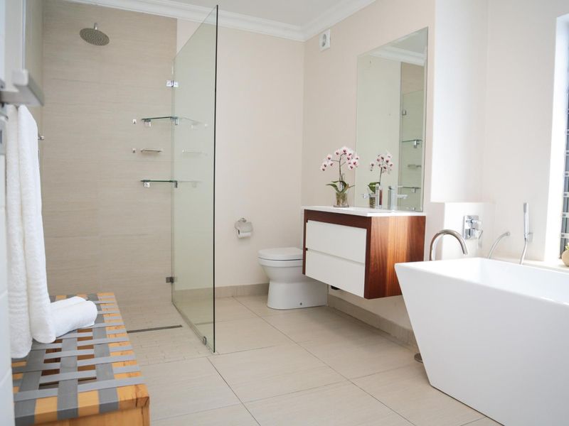Modern bathroom featuring a walk-in shower with glass screen, a sleek wall-mounted vanity, and a contemporary freestanding bathtub.