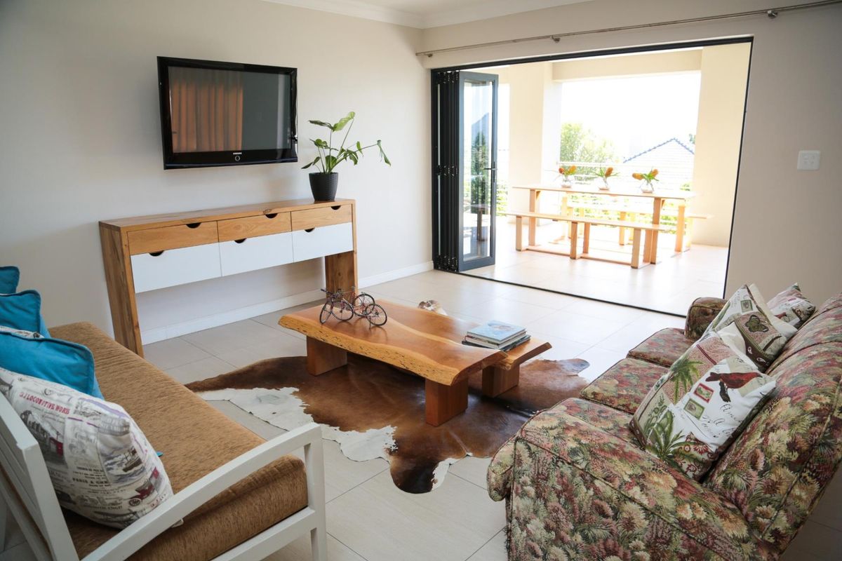 Bright living room featuring tiled flooring and large bi-fold doors that open onto a covered patio area.