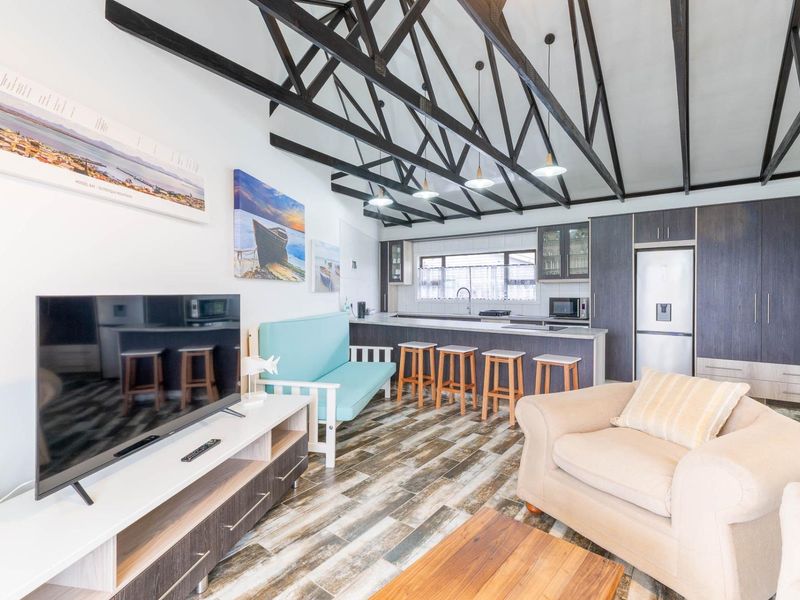 Open-plan living and kitchen area featuring high vaulted ceilings with exposed timber trusses, modern cabinetry, and a functional kitchen island.