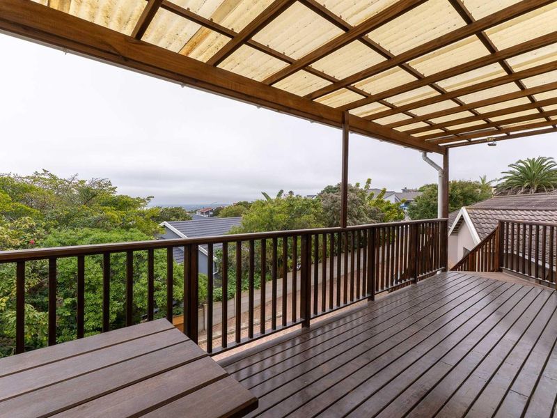 Spacious elevated timber balcony featuring a covered pergola roof, wooden balustrades, and scenic neighbourhood views.