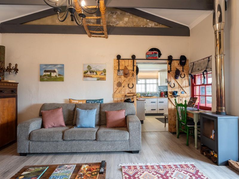 Cozy living room featuring exposed timber ceiling beams, a wood-burning stove, and sliding barn-style doors leading to the kitchen area.