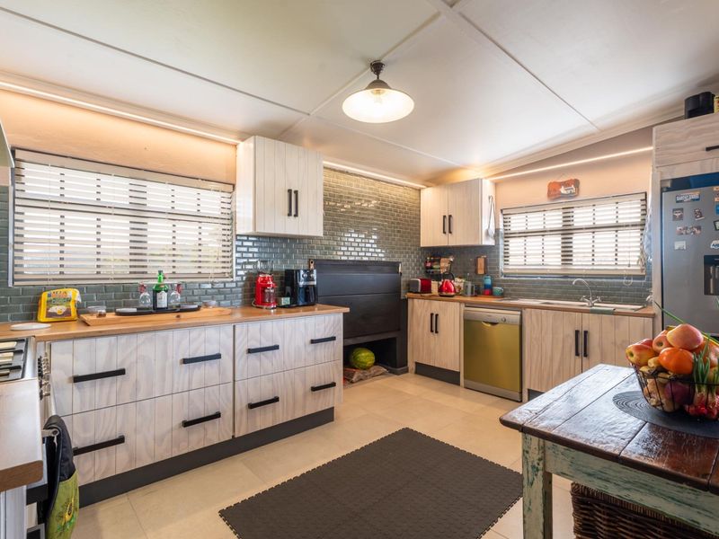 Modern kitchen featuring light wood-grain cabinetry, subway tile backsplash, integrated indoor braai, and functional workspace with ample storage.