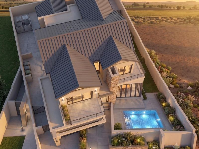 Aerial view of a modern residential property featuring a metal roof, swimming pool, stone accents, and landscaped outdoor areas at sunset.