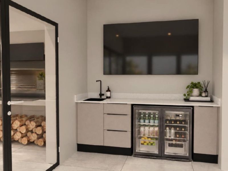 A modern, well-appointed bar area featuring sleek cabinetry, stone countertops, an integrated beverage cooler, and a stylish black sink fixture.