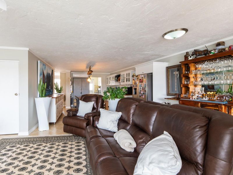 Spacious open-plan living area featuring tiled flooring and integrated kitchen cabinetry, offering a versatile layout for dining and relaxation.