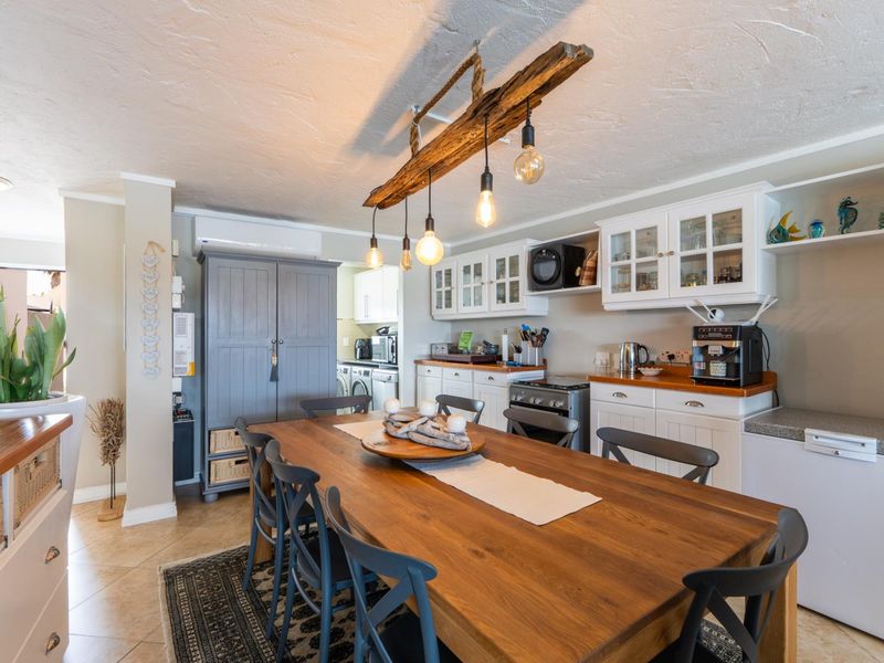 Open-plan dining and kitchen area featuring built-in cabinetry, timber countertops, and a rustic timber pendant light fixture.