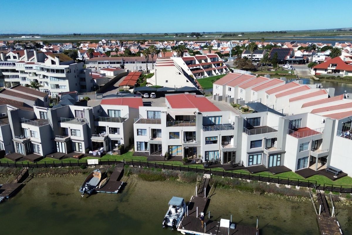 Aerial view of a waterfront townhouse complex featuring private jetties, balconies, and well-maintained communal grounds in a coastal setting.