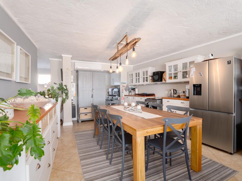 An open-plan kitchen and dining area featuring tiled floors, ample built-in cabinetry, and a split-system air conditioning unit.