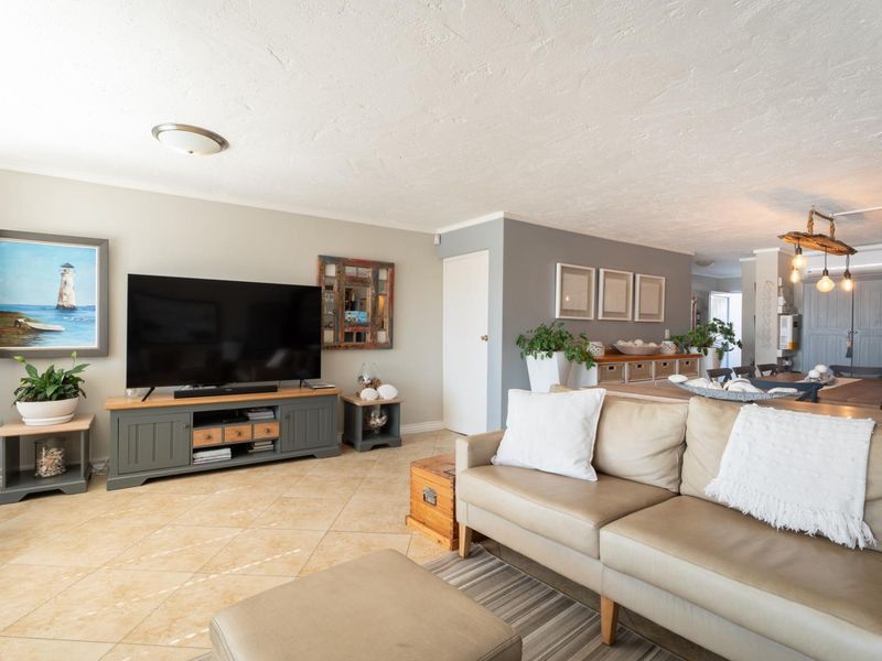 Spacious open-plan living area featuring neutral wall tones, tiled flooring, and integrated air conditioning, creating a comfortable and cohesive living and dining space.