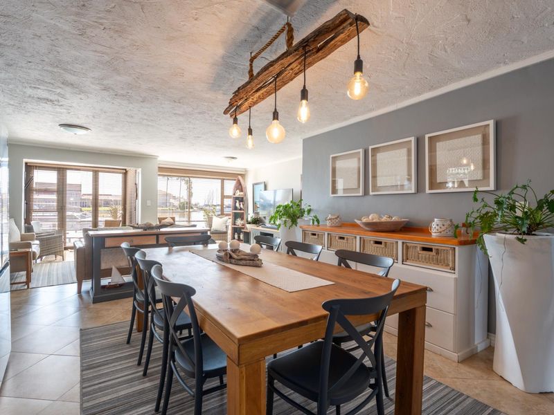 Spacious open-plan dining and living area featuring tiled floors, textured ceilings, and large sliding glass doors that provide ample natural light.