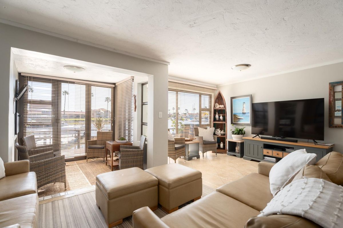 A bright and spacious living area featuring tiled flooring, large windows with venetian blinds, and a comfortable layout overlooking the exterior.