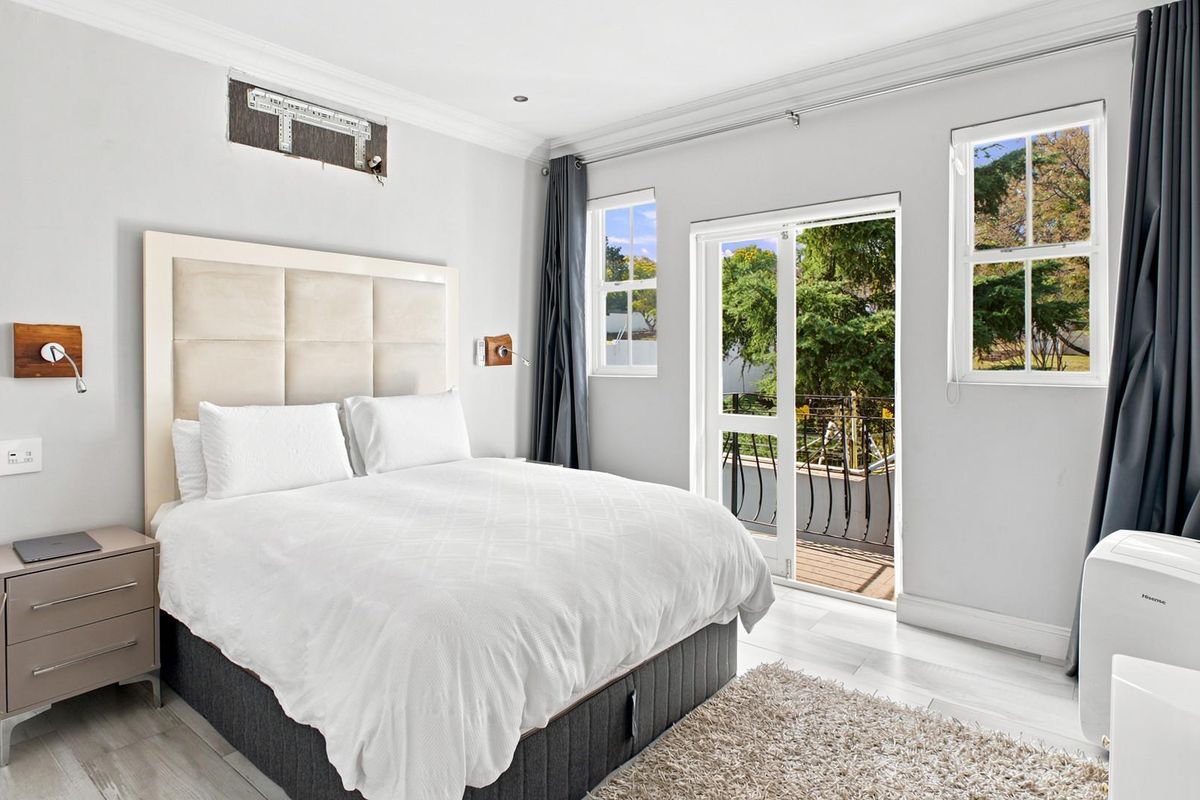 Bright bedroom featuring neutral finishes, coving, and direct access to a private balcony through sliding glass doors.